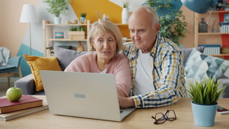 una pareja de ancianos usando una computadora portátil en casa