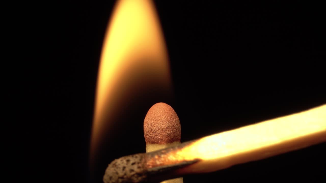 Closeup matchstick head being ignited and burning, macro, black background