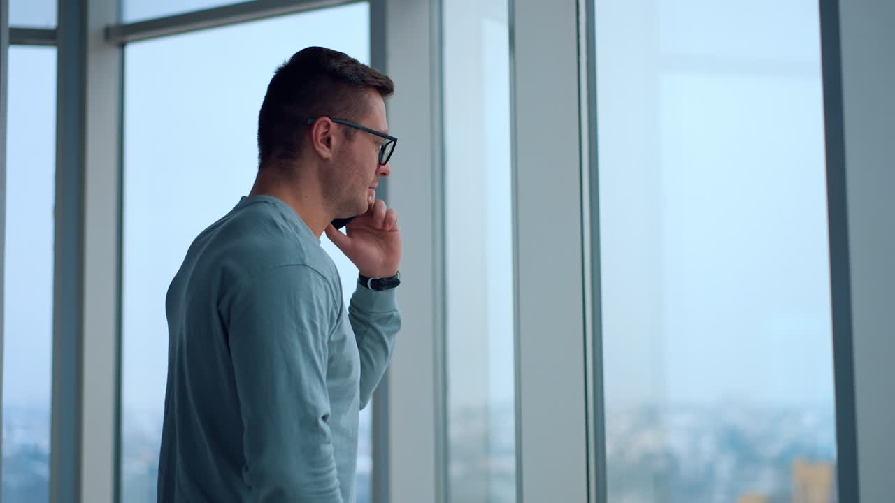 Uomo che parla al telefono alla finestra dell'ufficio