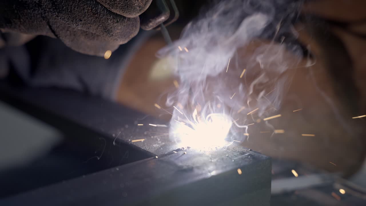 Welding metal in close up slow motion while sparks are flying away