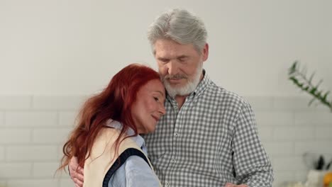 una pareja de ancianos enamorados de 60 a 70 años bailando lentamente en casa en la cocina