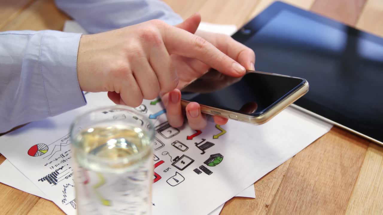 테이블 위 에 그래프 차트 와 디지털 태블릿 을 가진 책상 에서 휴대 전화 를 사용하는 사업가