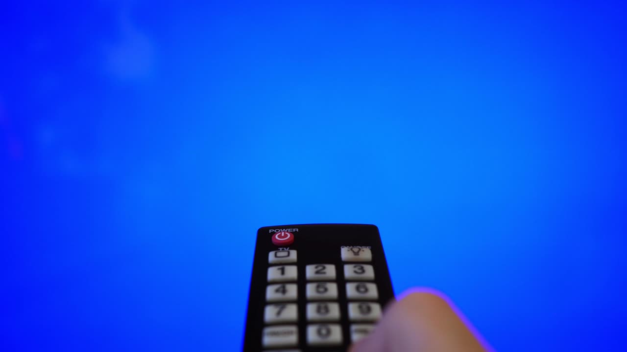 tv 화면을 가리키는 리모컨을 가진 남성 손. 파란색 크로마 키.