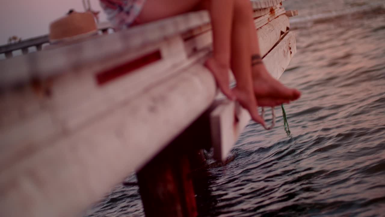 Young romantic couple sitting on wooden pier over the sea