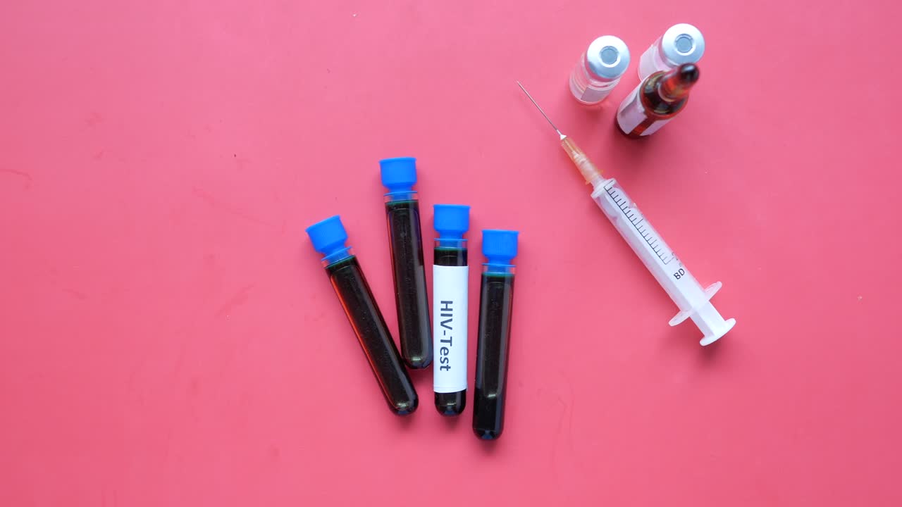 Hiv blood test tube and syringe on red background ,
