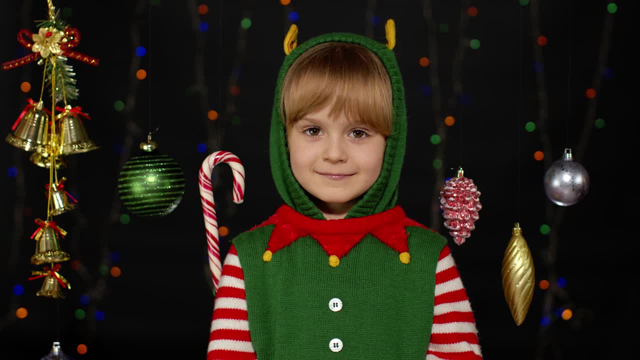 Girl in Christmas elf Santa helper costume waving greeting with hand. Hello, hi, greetings gesture