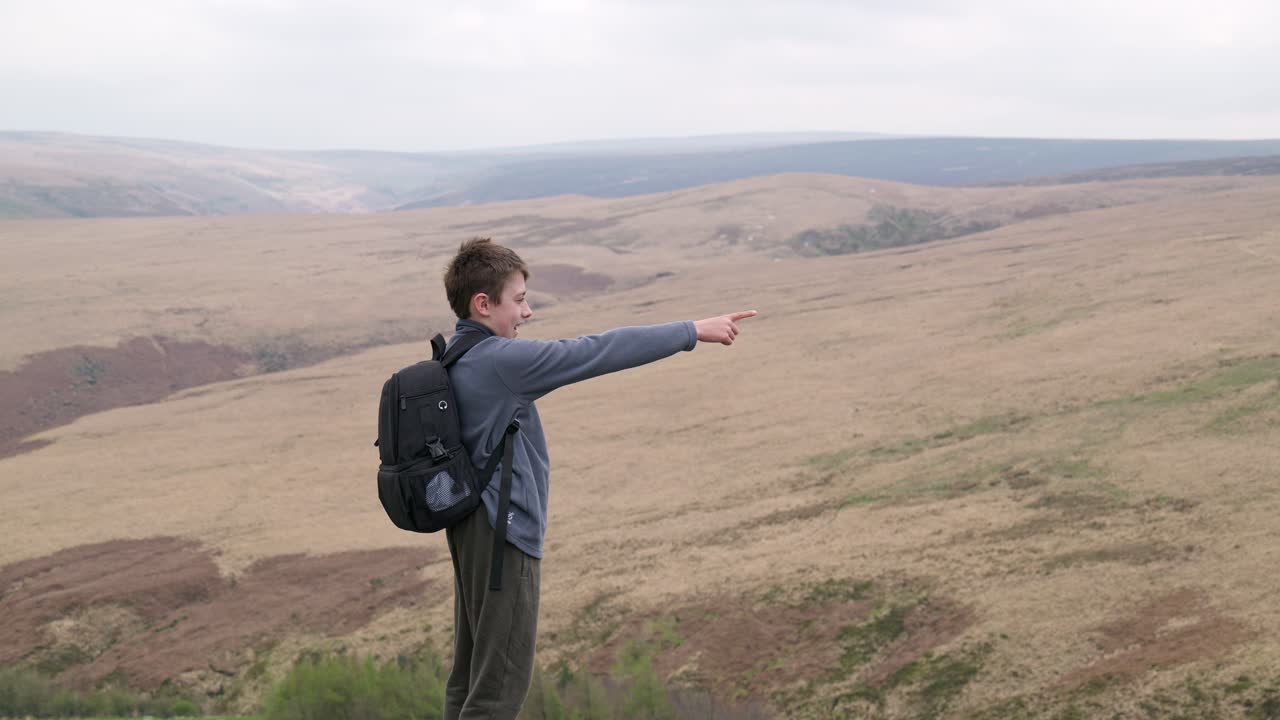 시골 언덕 꼭대기에 서 있는 야외의 어린 소년, 습지의 전망을 감상