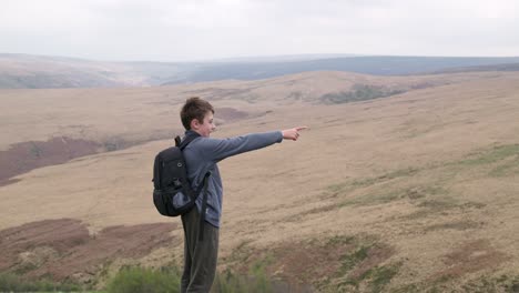 young boy outdoors standing on a countryside hill top, admiring the moorland views