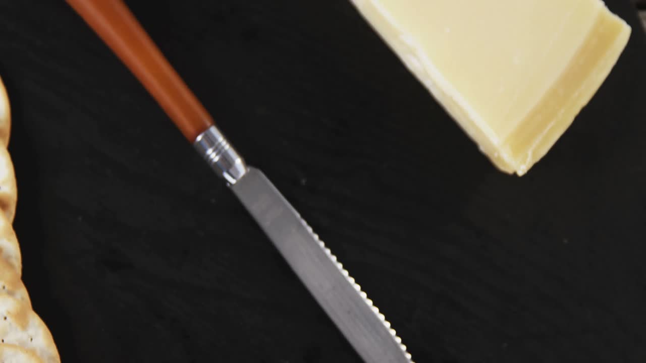 una rebanada de queso con galletas crujientes y cuchillo