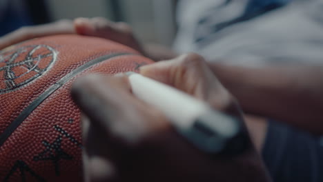 hands of sportsman making a sign on basketball with marker