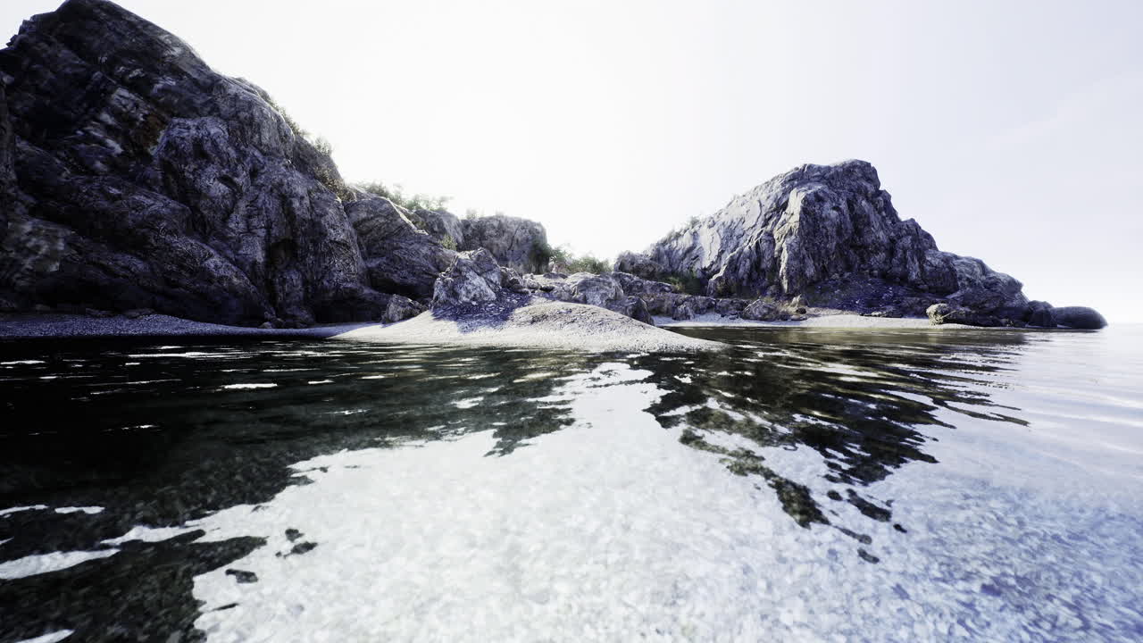 Peaceful shoreline with rocky cliffs and clear water at sunrise