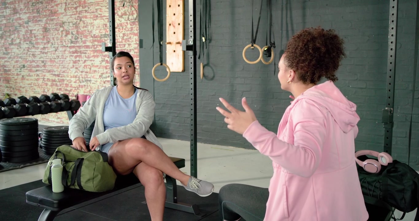 Diverse female friends meeting at fitness gym, hugging, unpacking straps, warming up for workout