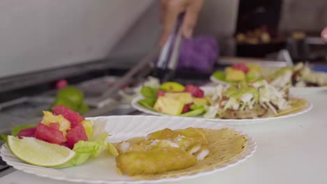 un chef de orden corta prepara tacos de pescado en la cocina de un restaurante