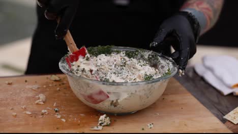 el hombre mezcla ingredientes de pescado picados con cebollino en un recipiente en el fumador.