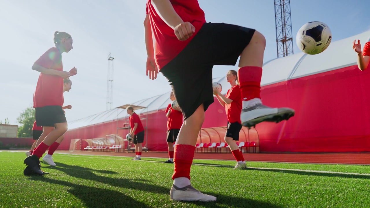 Giovani calciatrici che si allenano nel controllo del pallone sul campo.