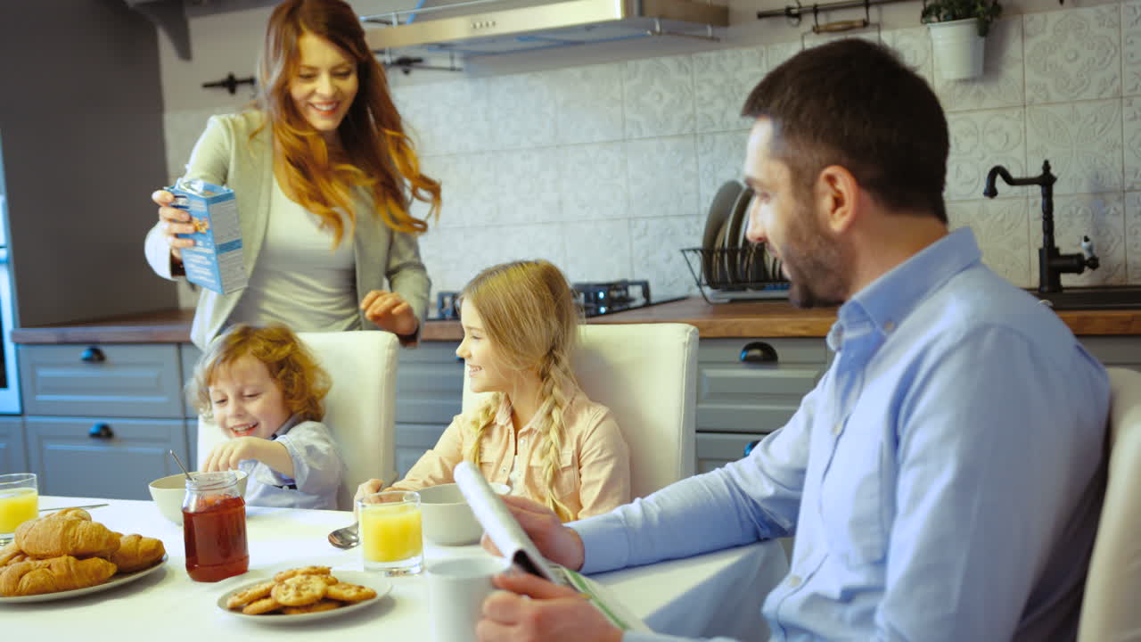 una madre sirviendo cereal a sus hijos mientras su esposo los mira