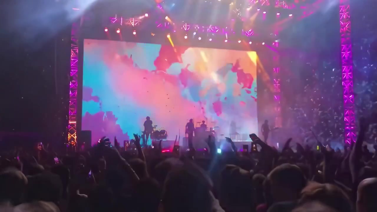 Begejstret publikum jubler til en livlig livekoncert med konfetti og pyroteknik