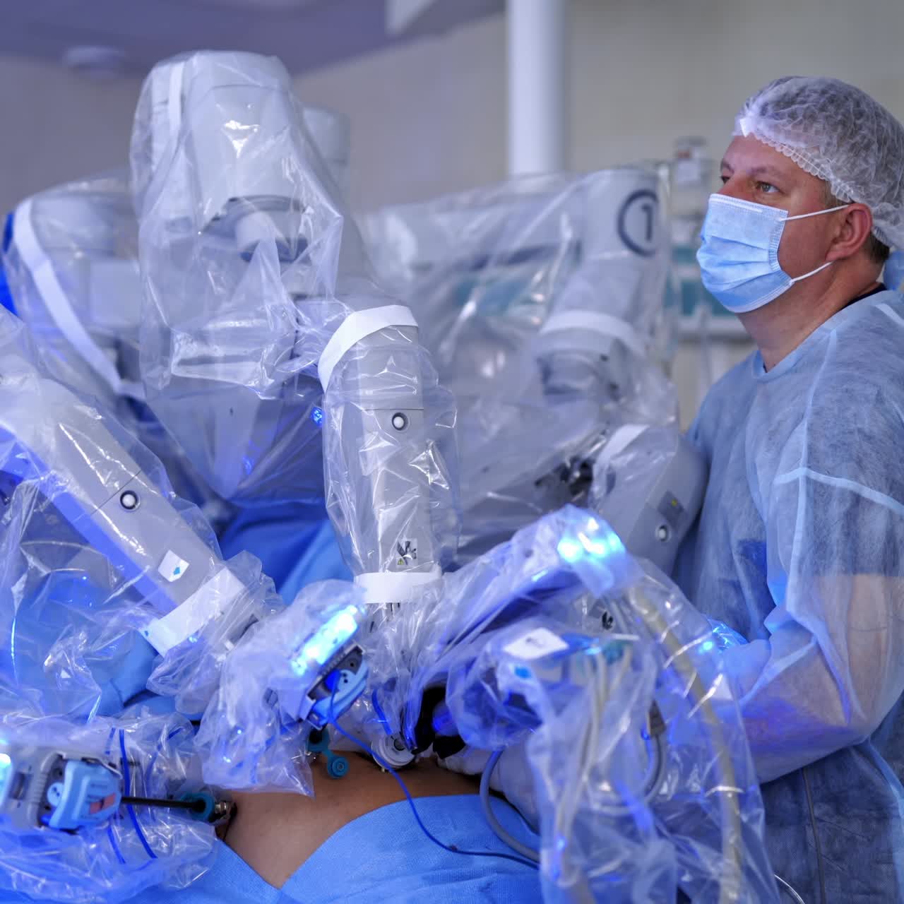 Surgery with robotic equipment. Doctor in medical uniform controls the work of futuristic machine with robotic arms on medical monitor background in hospital.