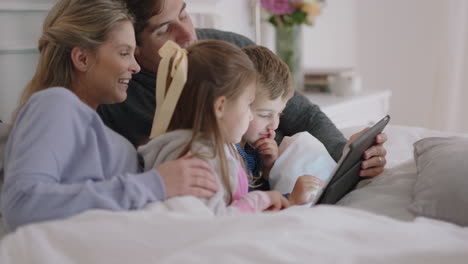 Familia-Feliz-Usando-Una-Tableta-En-La-Cama,-Madre-Y-Padre-Con-Niños-Viendo-Entretenimiento-Jugando-En-Un-Dispositivo-De-Pantalla-Táctil,-Aprendiendo-A-Divertirse-Juntos-El-Fin-De-Semana-Por-La-Mañana,-Imágenes-De-4k