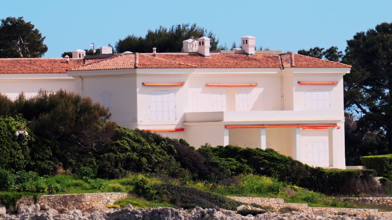 View of an orange villa surrounded by greenery on the shore, in the south of France