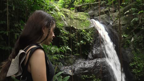 young woman tourist visits bali jungle waterfall in goa gajah temple, rainforest indonesia