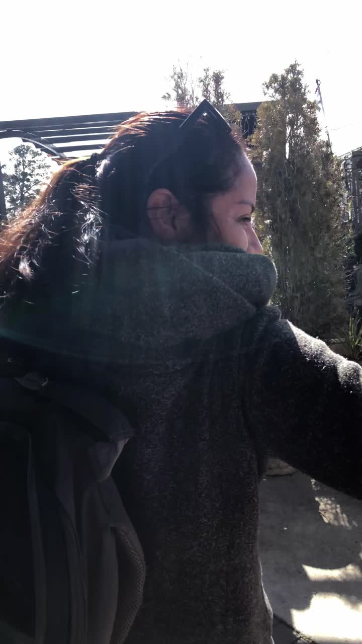 Woman with Backpack Stepping Out of a Door into Sunny Outdoor Area