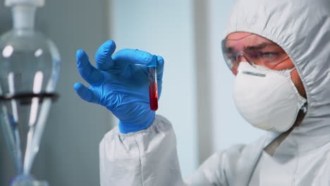 científico con muestra de sangre con traje de protección