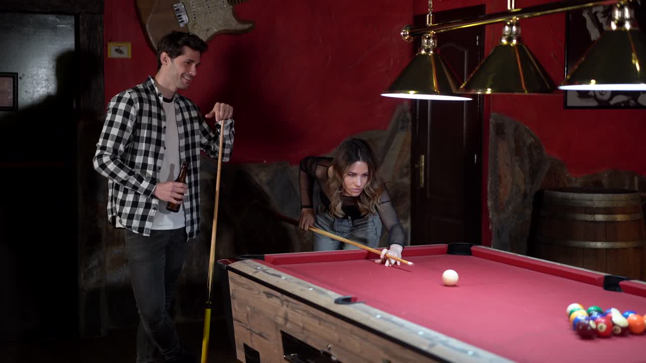 Happy couple playing billiards in pub
