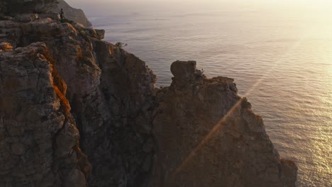 Beautiful-sunset-along-coastline-of-tall-jagged-rocky-cliffs-and-ocean