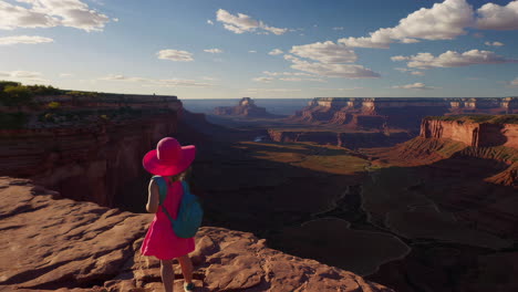 little girl in pink hat overlooking a vast canyon landscape