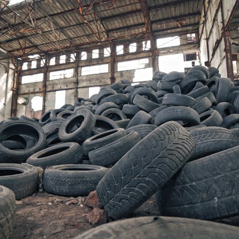 black junk tires lying on the floor in the old abandoned building. many used rubber tires from different vehicles are on a desolate plant inside.