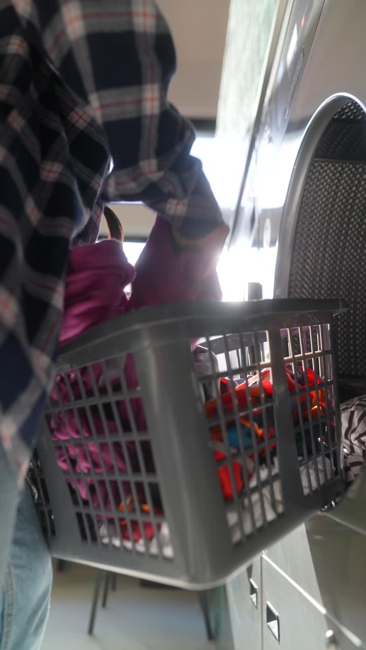 persona que pone la ropa en una lavadora