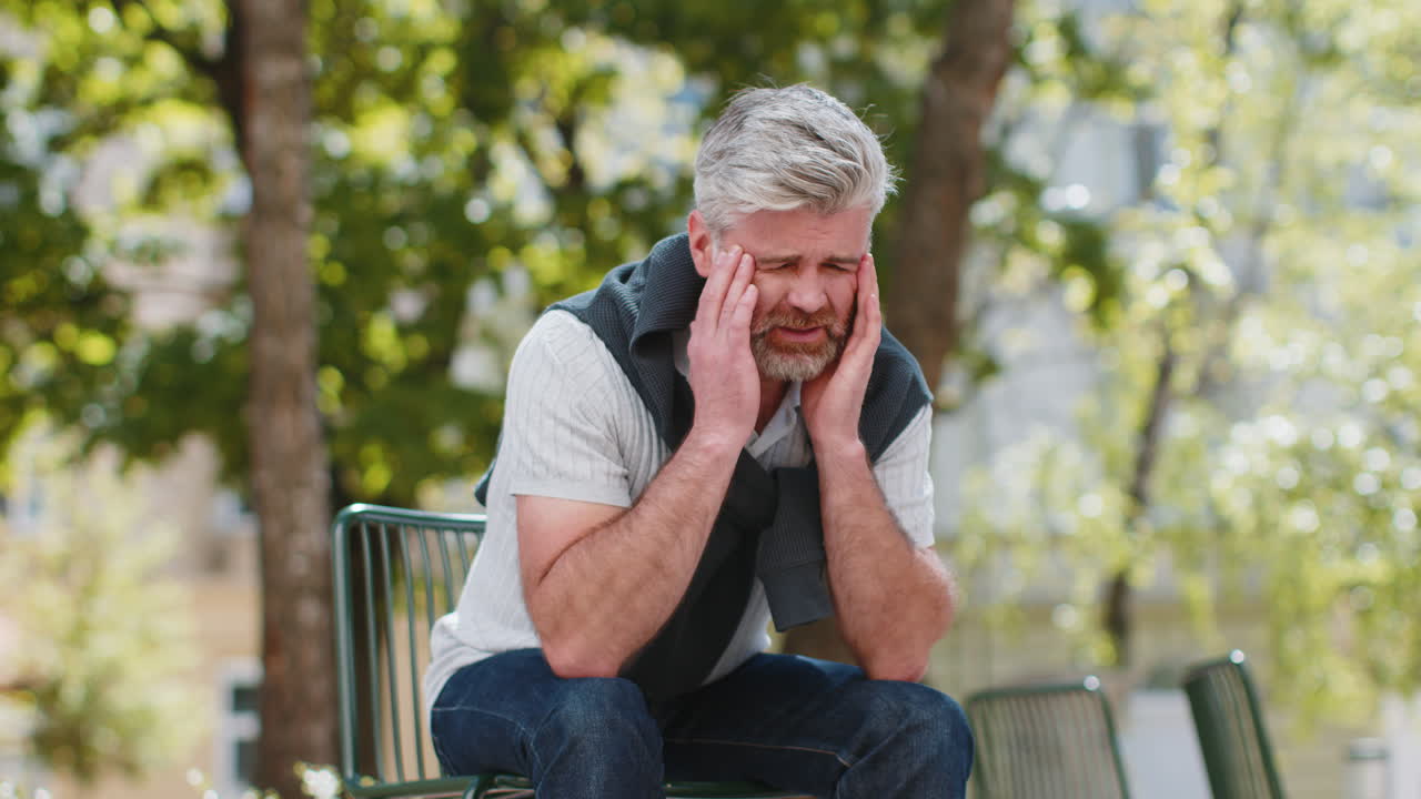 Exhausted mature man rubbing temples to cure headache problem suffering from tension migraine