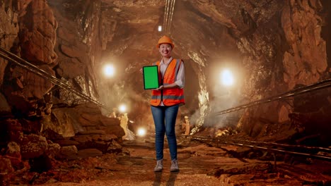 woman engineer in mine holding tablet with green screen