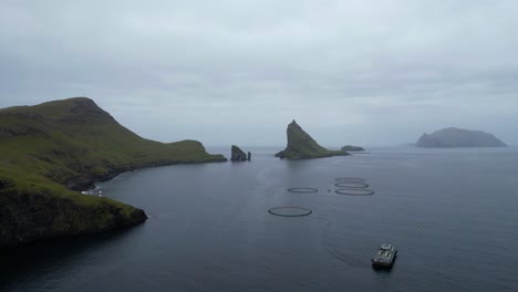 granja de acuicultura de salmón con frente de barco de pesca drangarnir y tindholmur en vagar, islas feroe