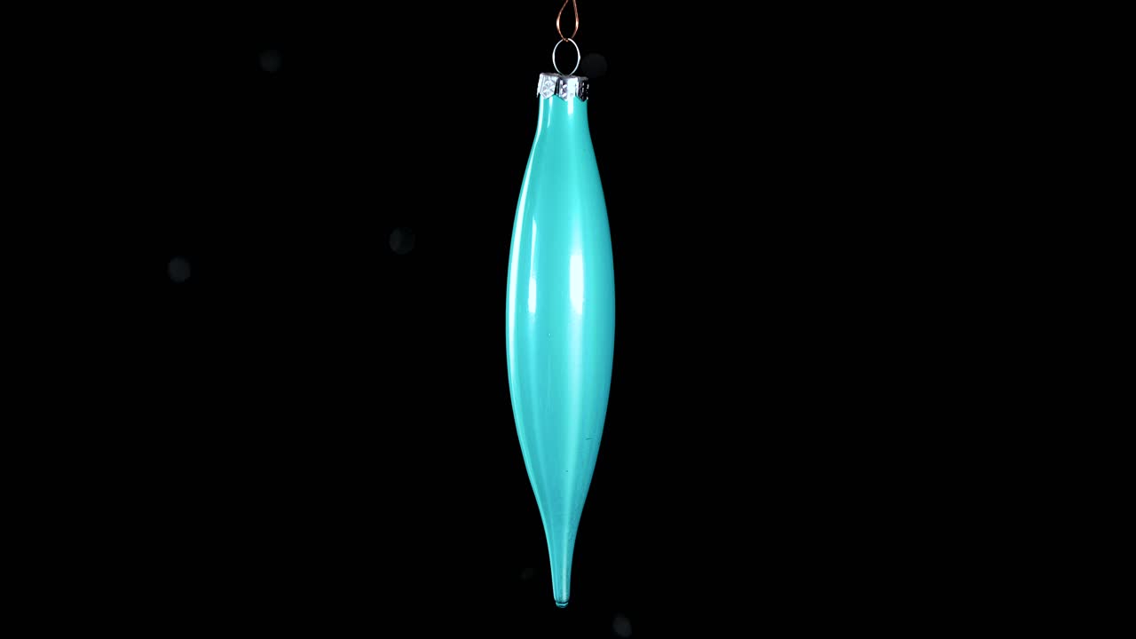 single blue turquoise Christmas cone ornament with black background, close up