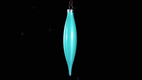 single blue turquoise christmas cone ornament with black background, close up