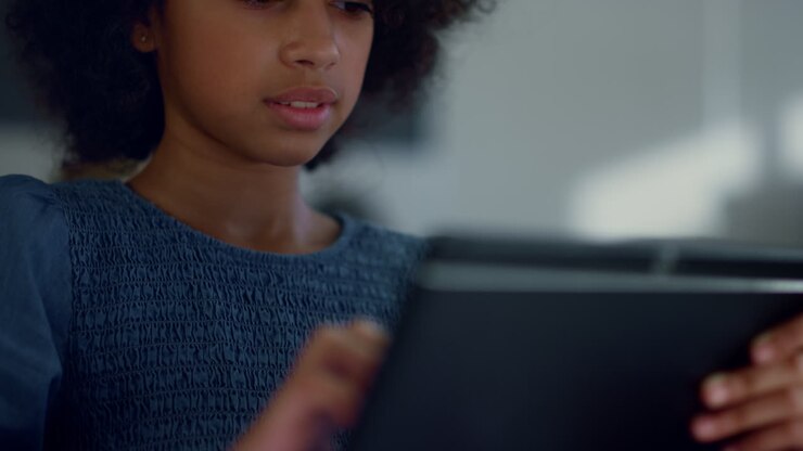Alunna che tiene un tablet in mano. Bambina che impara online sul tablet.
