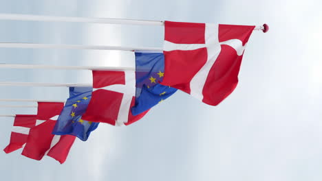 denmark and eu flag on flagpole waving on moody cloudy day