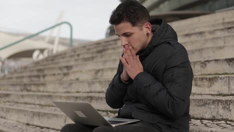 joven pensativo trabajando con una computadora portátil al aire libre