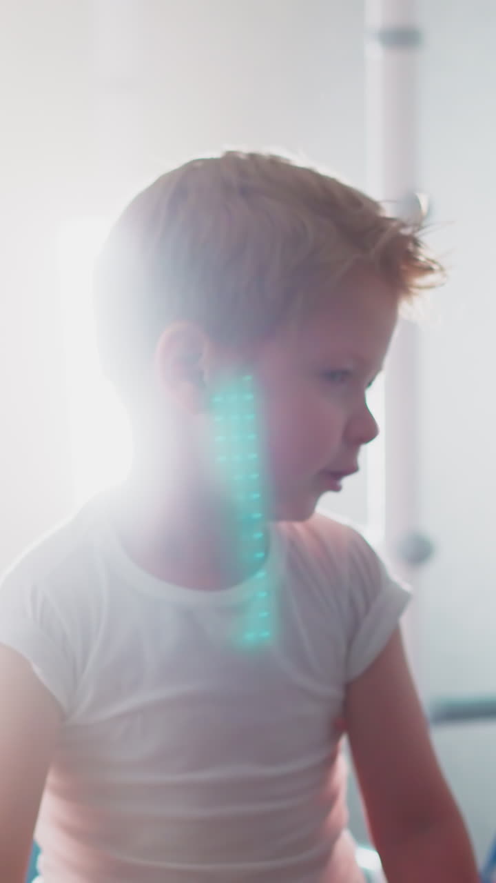 Cute toddler warms up before intensive training in gym. Little boy stands against gymnastic wall bars and bright lamp illuminating room slow motion