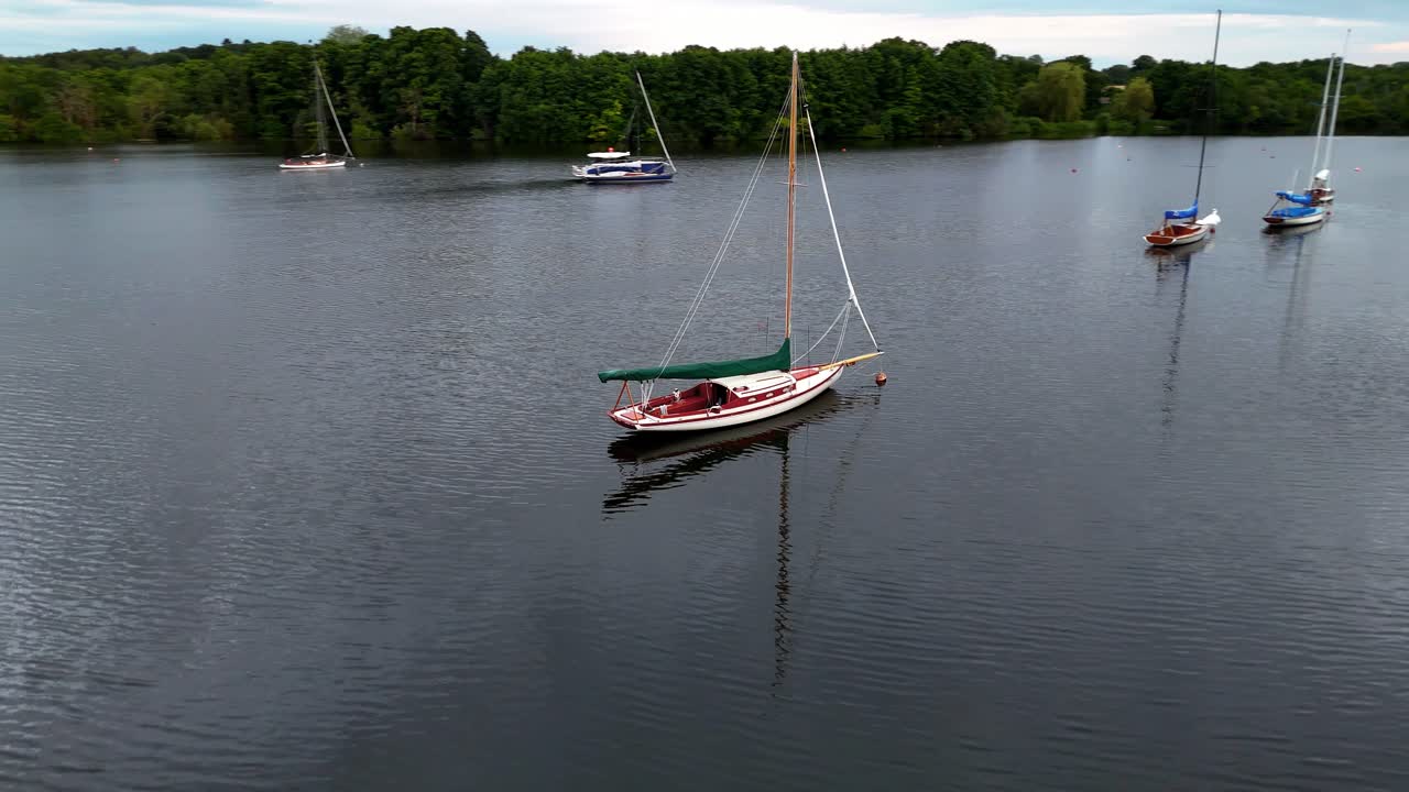 An aerial view of a lake with several sailboats anchored in the calm water