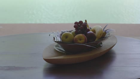 close up of a tropical decorated tray of fruit being put down on a table with a pool in the background