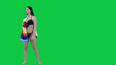 An-attractive-Caucasian-model-walking-in-a-bikini-and-towel-looking-for-a-spot-in-front-of-a-green-screen