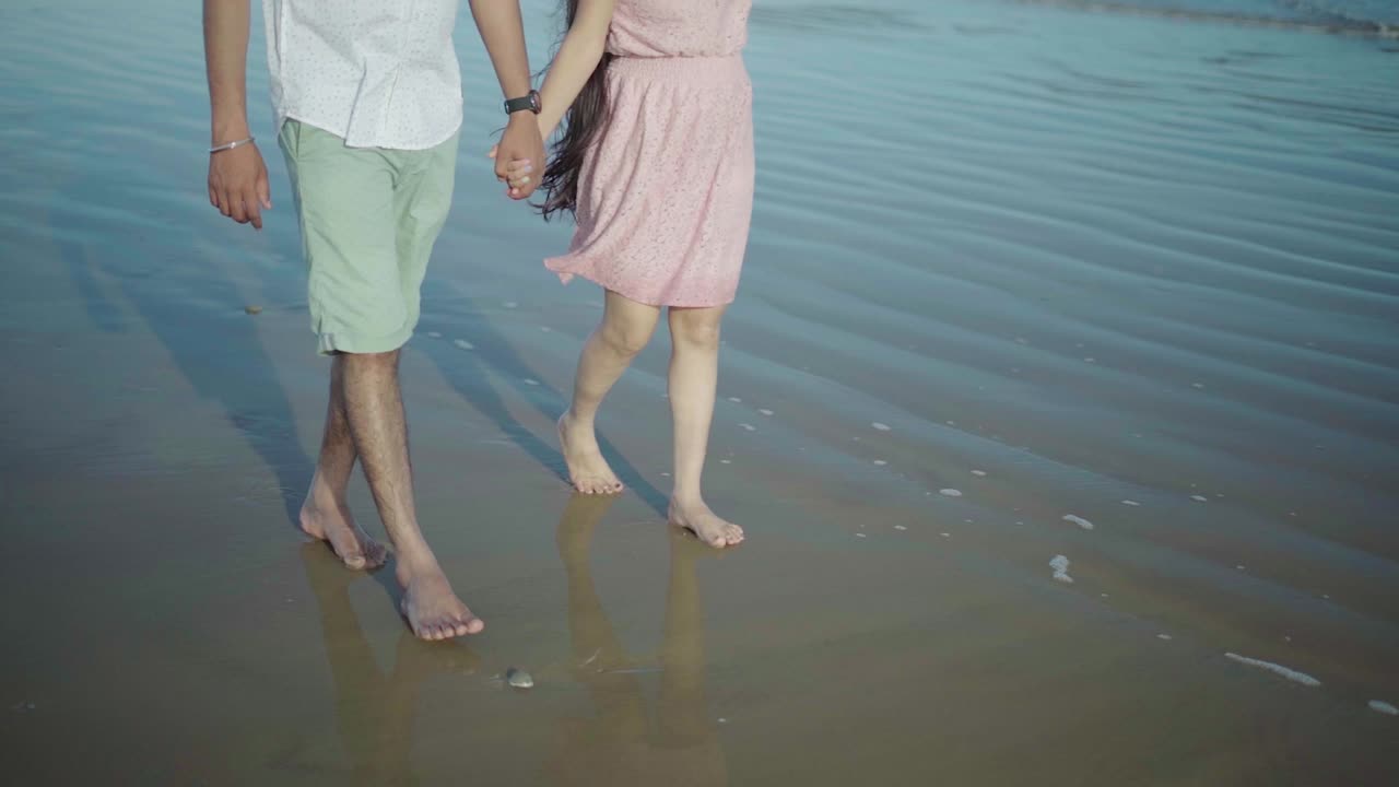 아침에 해변을 따라 걷는 인도 커플의 슬로우 모션 샷