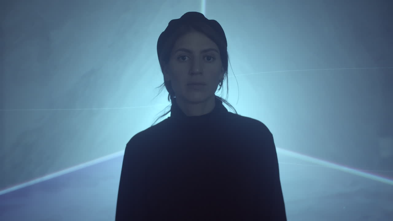 женщина ходит в лазерном туннеле и смотрит на камеру