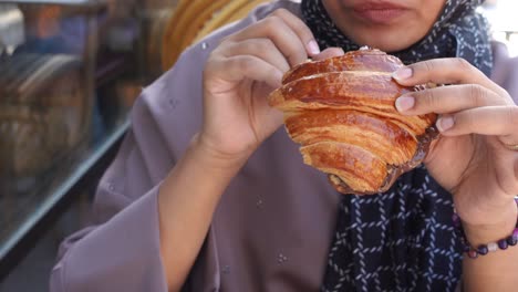 una mujer comiendo un croissant de chocolate.