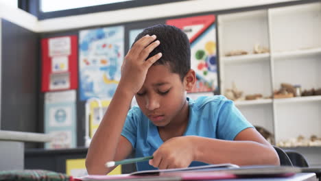 In-a-school-setting,-in-a-classroom,-a-young-African-American-student-concentrates-on-his-studies