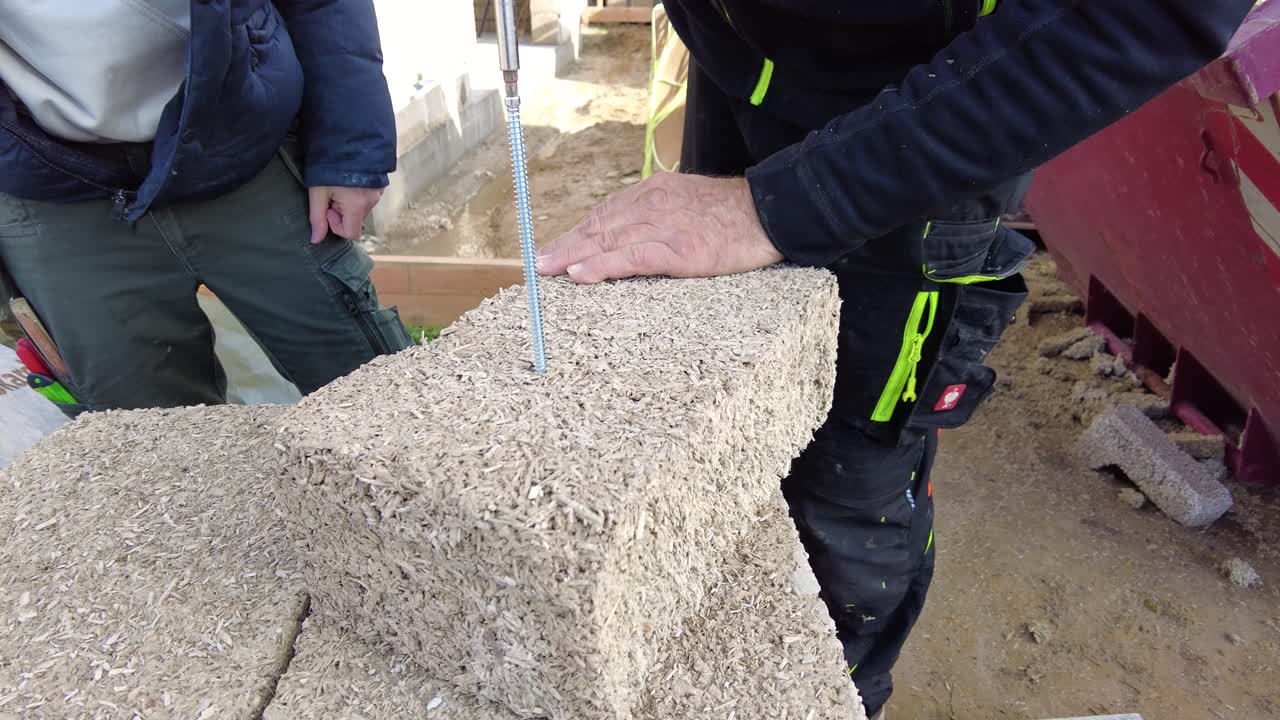 hempcrete 블록에 긴 나사를 뚫는 남자