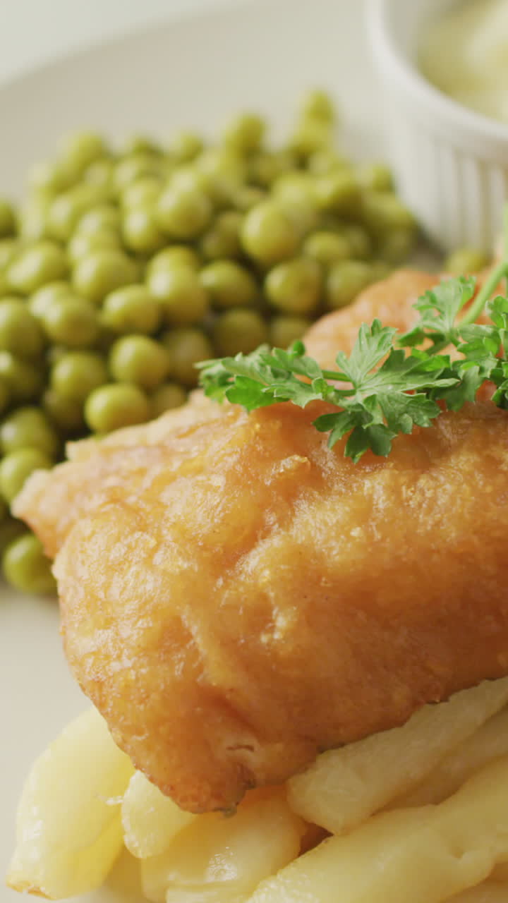 video de pescado, papas fritas y guisantes en un plato con salsa